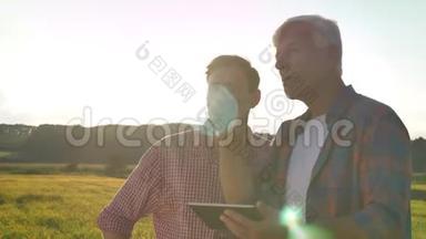 老爸爸教儿子农业，拿着石碑，站在麦田里，日落时美丽的景色